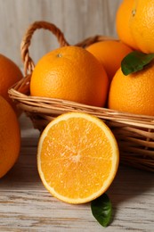 Photo of Many whole and cut oranges on light wooden table, closeup