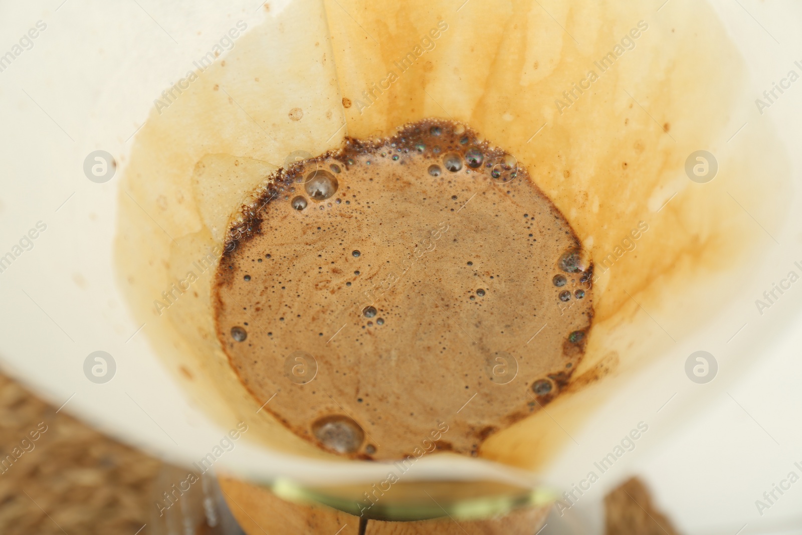 Photo of Paper filter with aromatic drip coffee in glass chemex coffeemaker, closeup