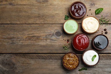 Photo of Many different sauces on wooden table, flat lay. Space for text