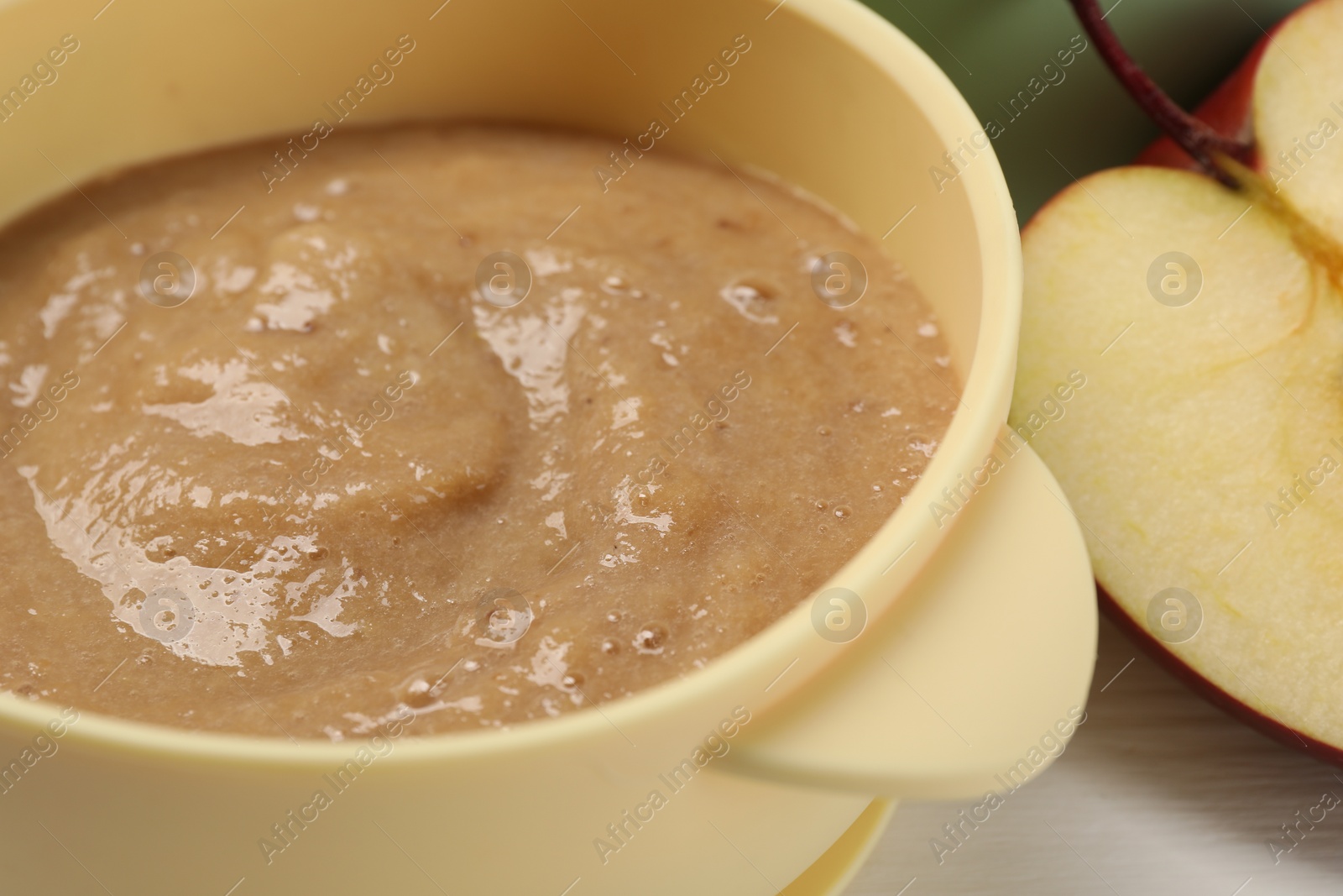 Photo of Baby food. Bowl with banana puree on white table, closeup