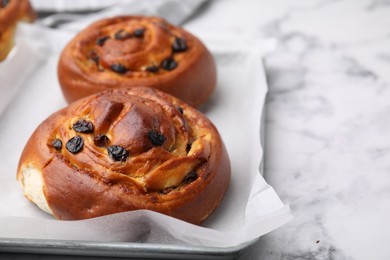 Photo of Delicious rolls with raisins on white marble table, closeup with space for text. Sweet buns