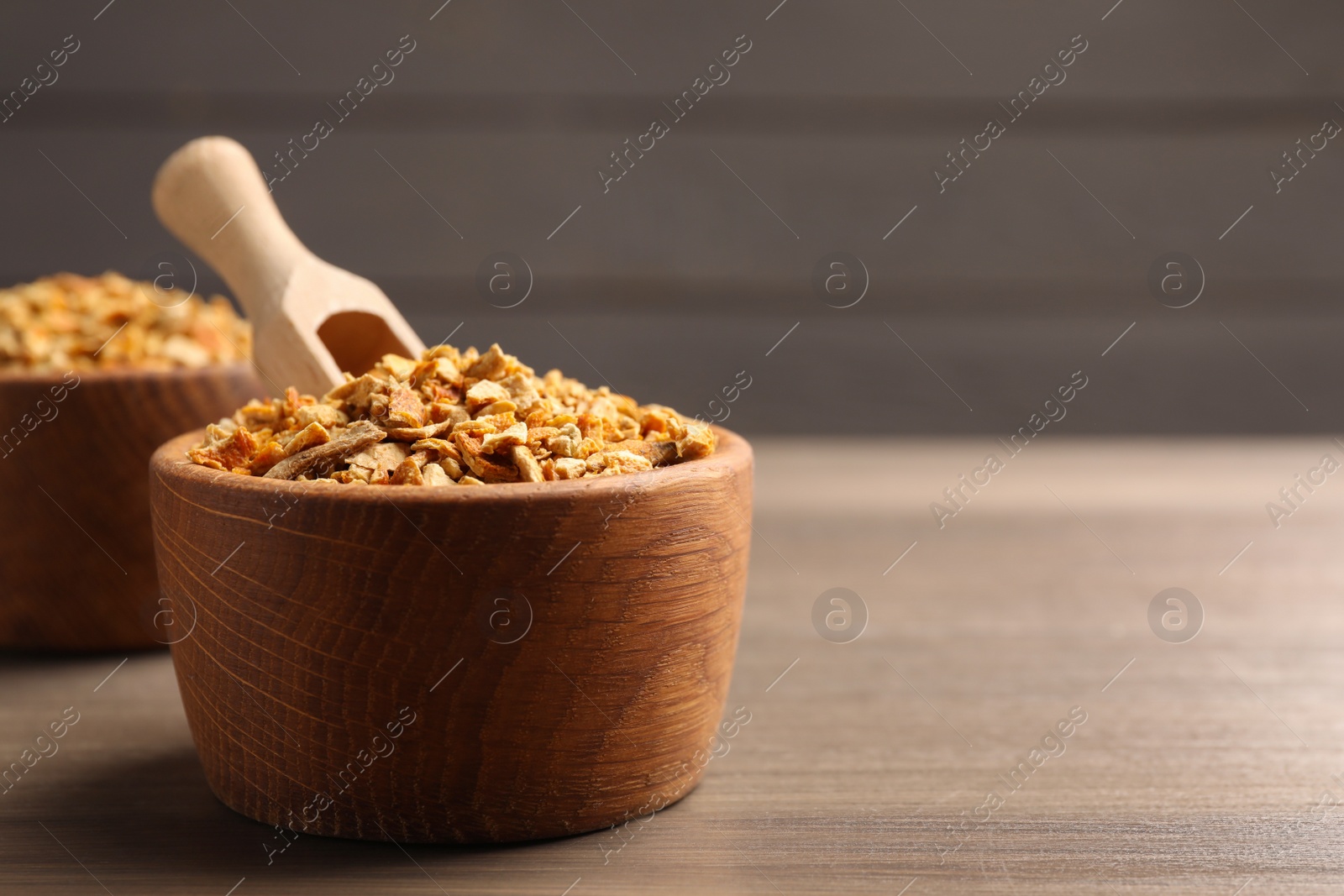 Photo of Bowls of dried orange zest seasoning on wooden table. Space for text