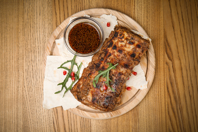 Photo of Delicious grilled ribs served on wooden table, top view