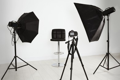 Photo of Empty chair in front of camera and professional lighting equipment indoors. Photo studio set
