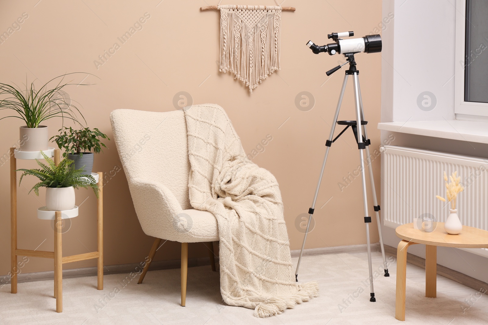 Photo of Tripod with modern telescope in stylish room