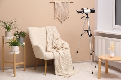 Photo of Tripod with modern telescope in stylish room