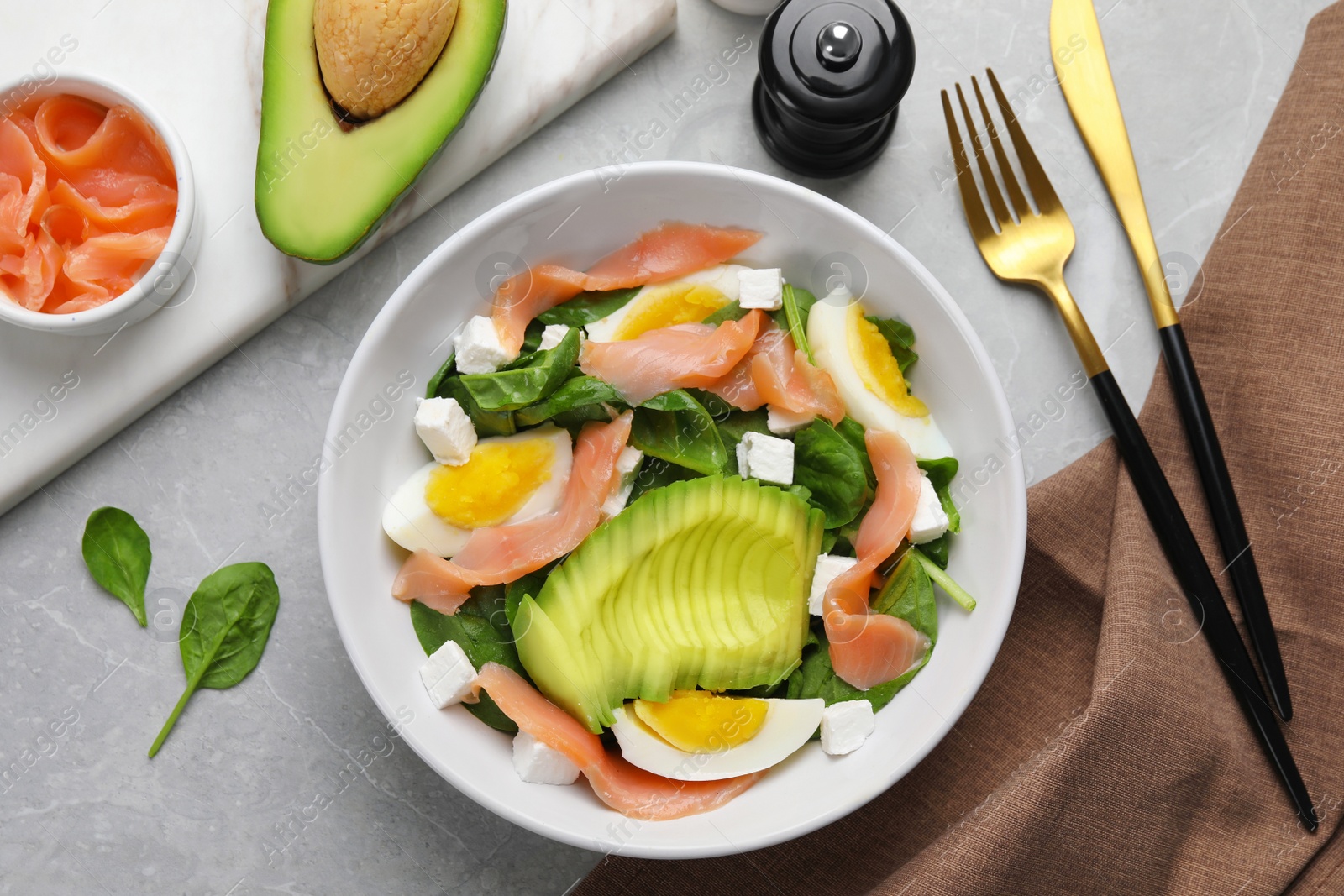 Photo of Delicious salad with boiled egg, salmon and avocado served on light grey marble table, flat lay