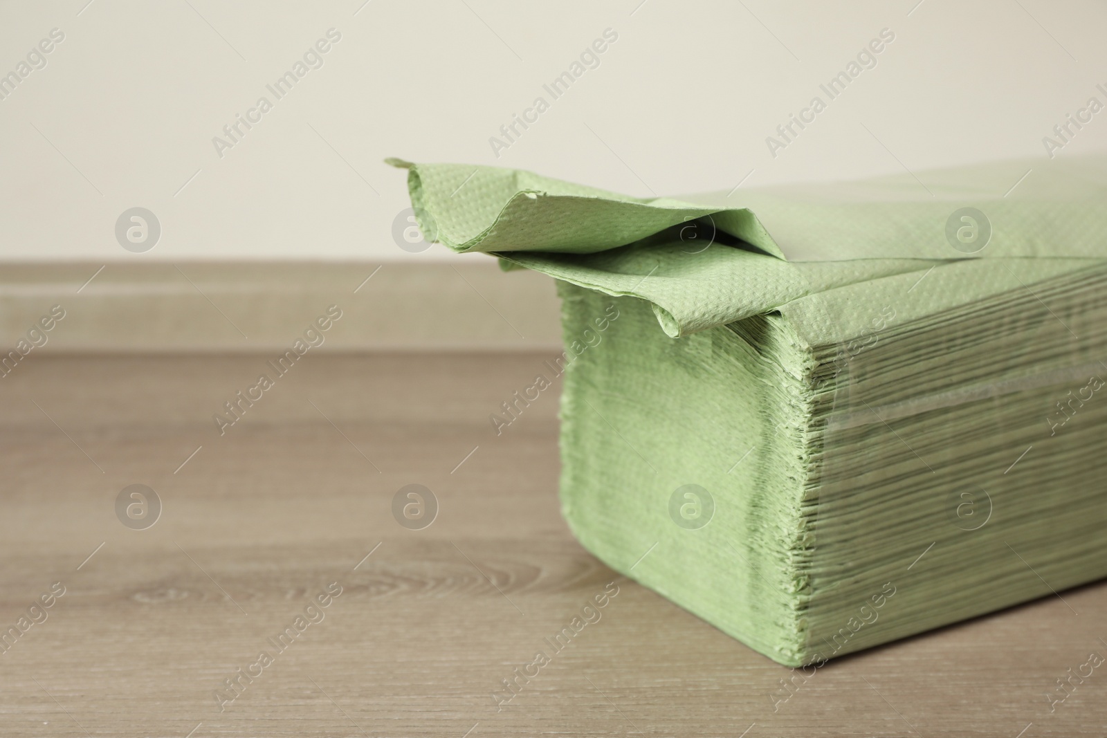 Photo of Stack of green paper towels on wooden table, closeup. Space for text