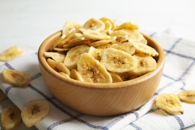 Photo of Wooden bowl with sweet banana slices on table. Dried fruit as healthy snack