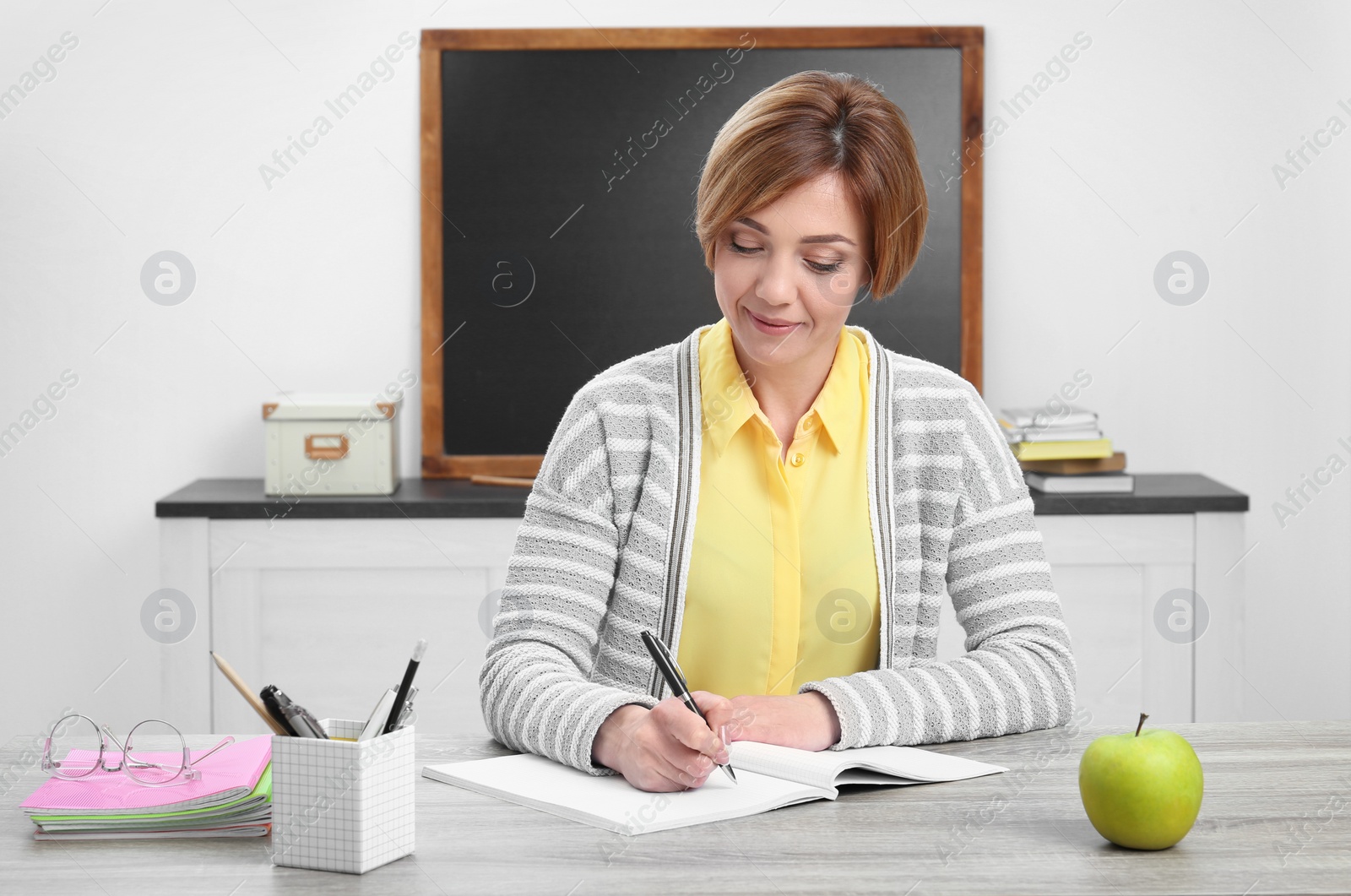 Photo of Portrait of female teacher sitting at table in classroom