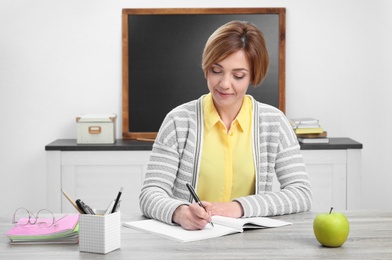 Photo of Portrait of female teacher sitting at table in classroom