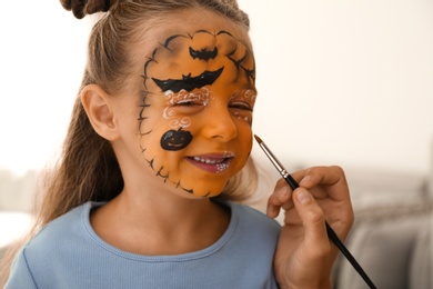 Artist painting face of little girl indoors