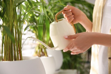 Photo of Woman watering house plant near window indoors, closeup
