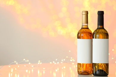 Photo of Bottles of wine on table against blurred lights. Space for text