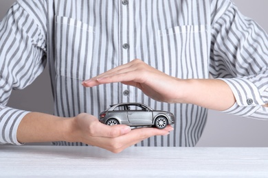 Insurance agent covering toy car at table, closeup
