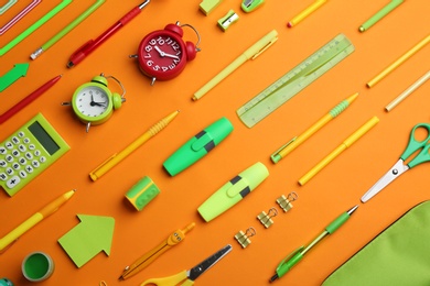 Different bright school stationery on orange background, flat lay