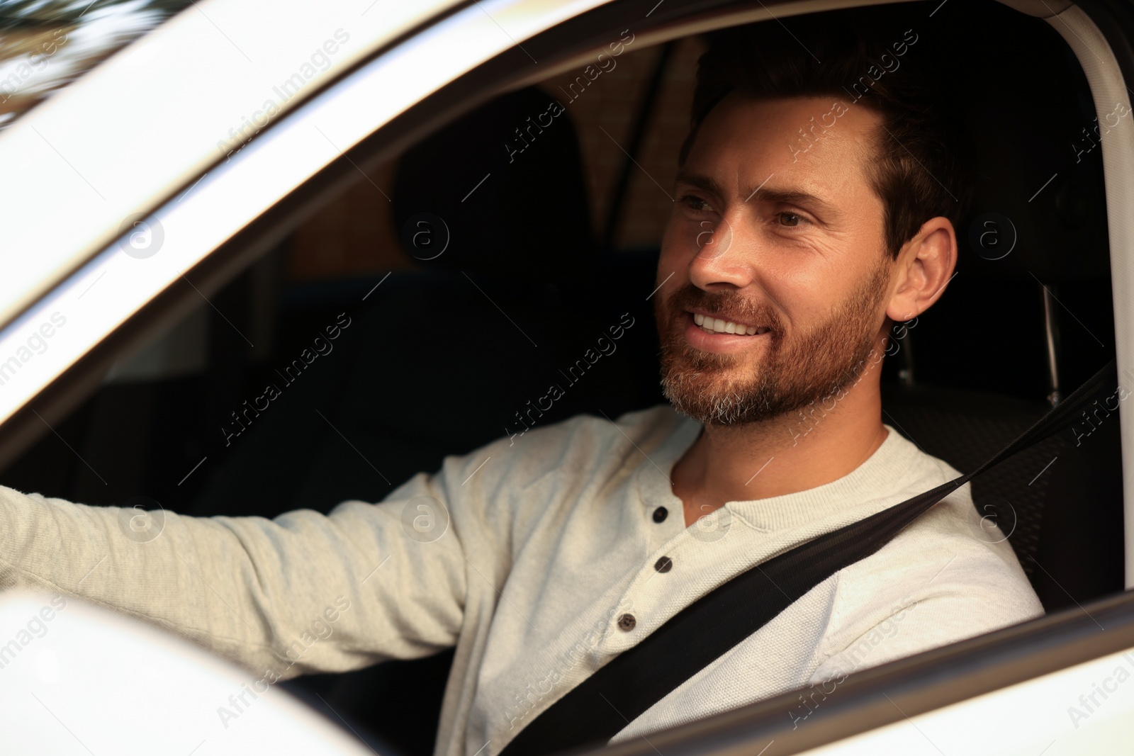 Photo of Enjoying trip. Happy bearded man driving his car, view from outside