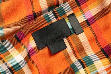 Photo of Blank clothing label on checkered apparel, closeup