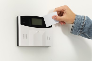 Home security system. Man using key card indoors, closeup