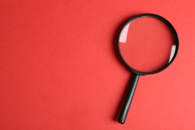 Photo of Top view of magnifying glass on red background, space for text. Search concept