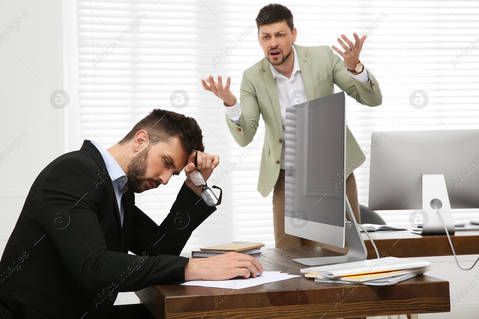 Photo of Boss screaming at employee in office. Toxic work environment