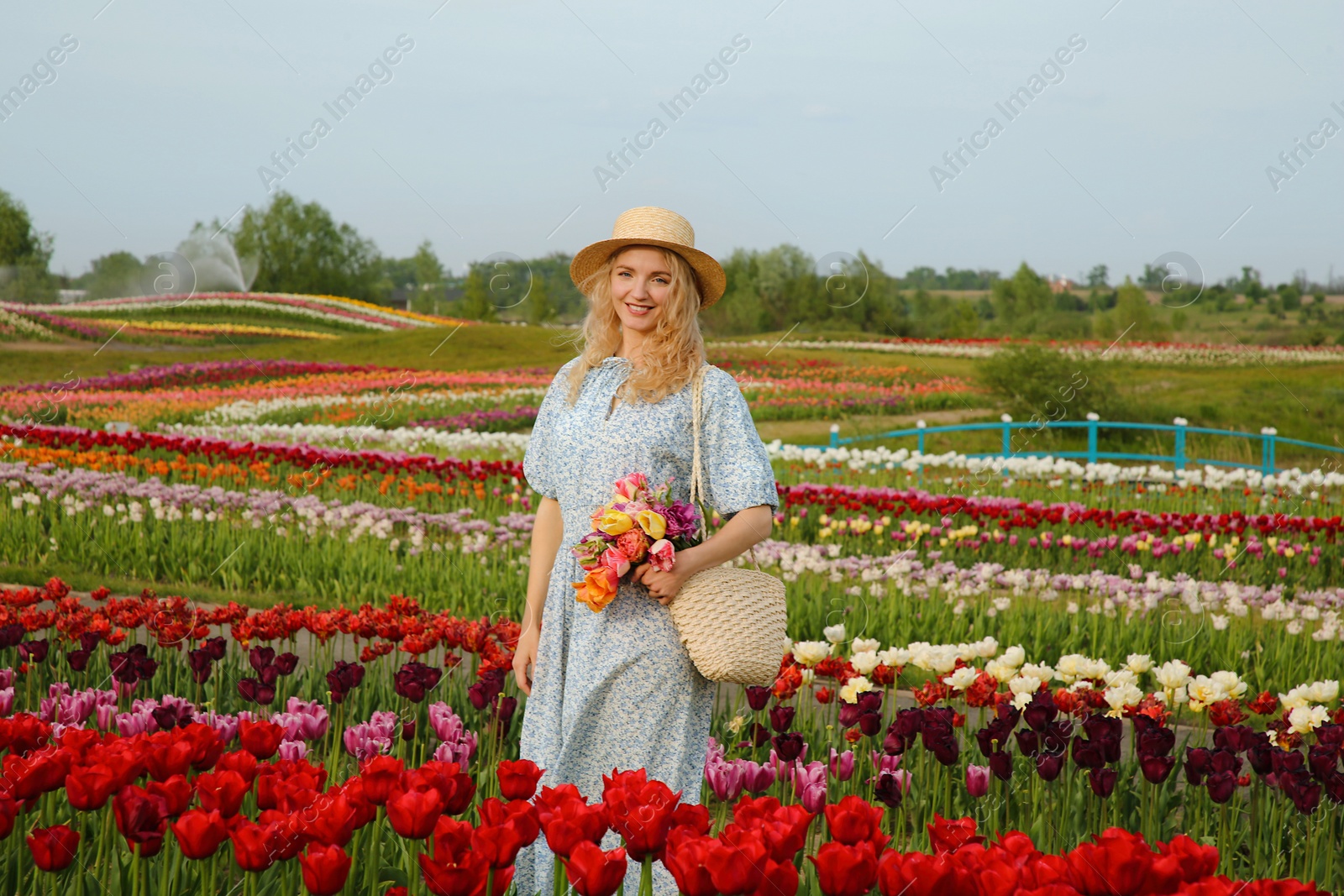 Photo of Woman with bag of spring flowers in beautiful tulip field