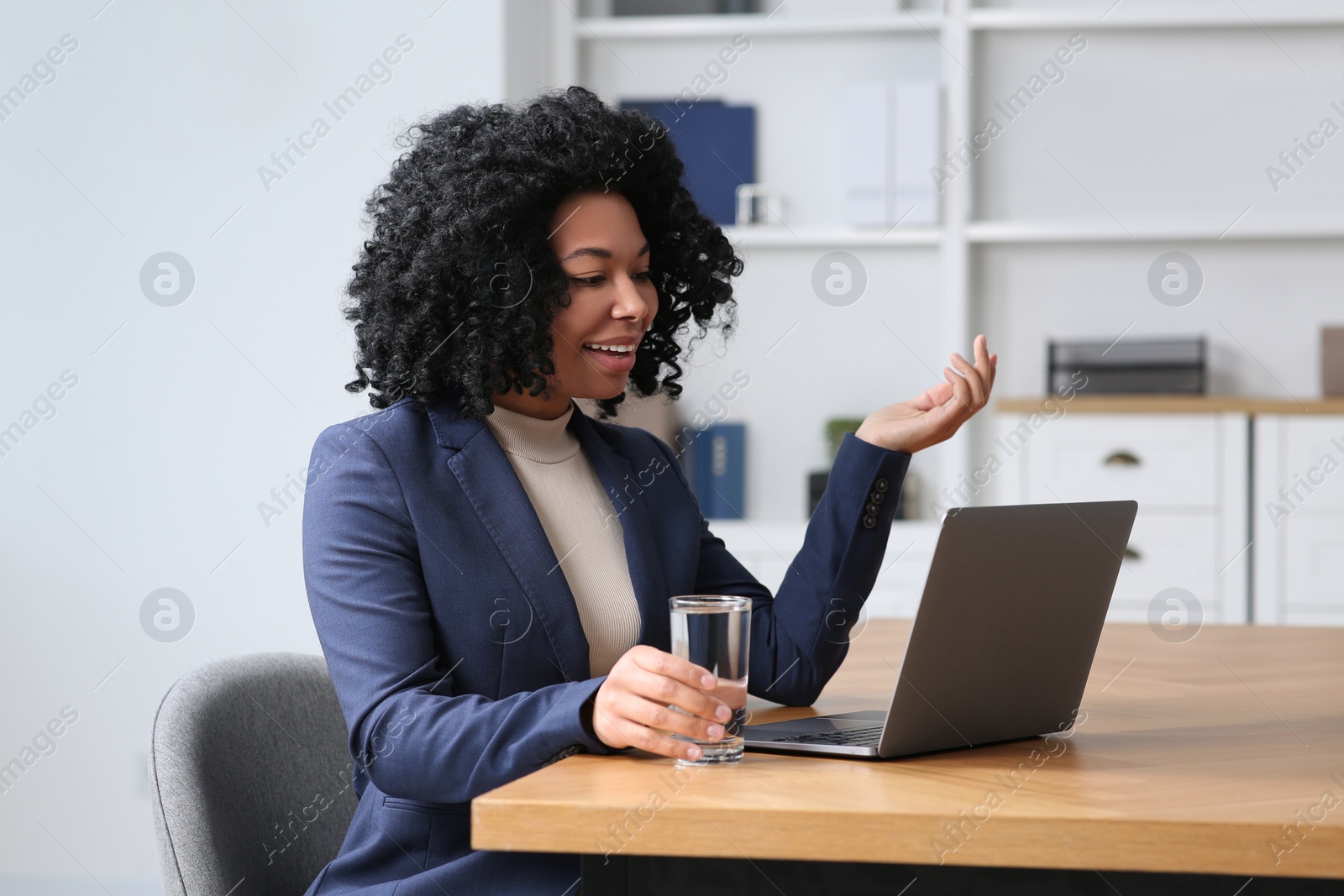 Photo of Young woman having video chat via laptop at table in office