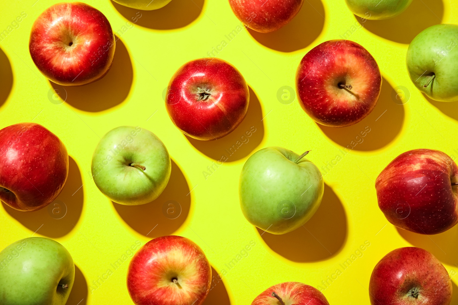 Photo of Many different ripe apples on yellow background