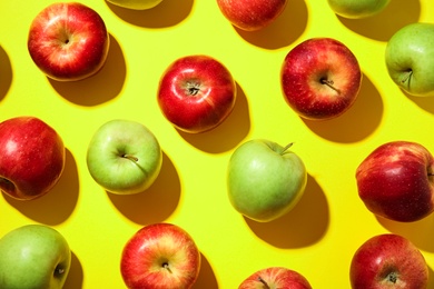 Photo of Many different ripe apples on yellow background