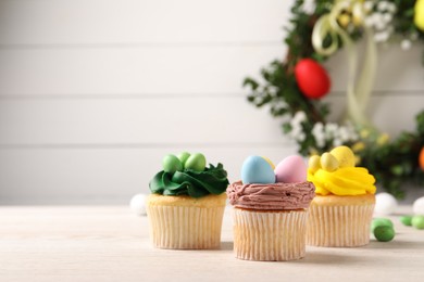 Photo of Tasty decorated Easter cupcakes on wooden table, closeup. Space for text