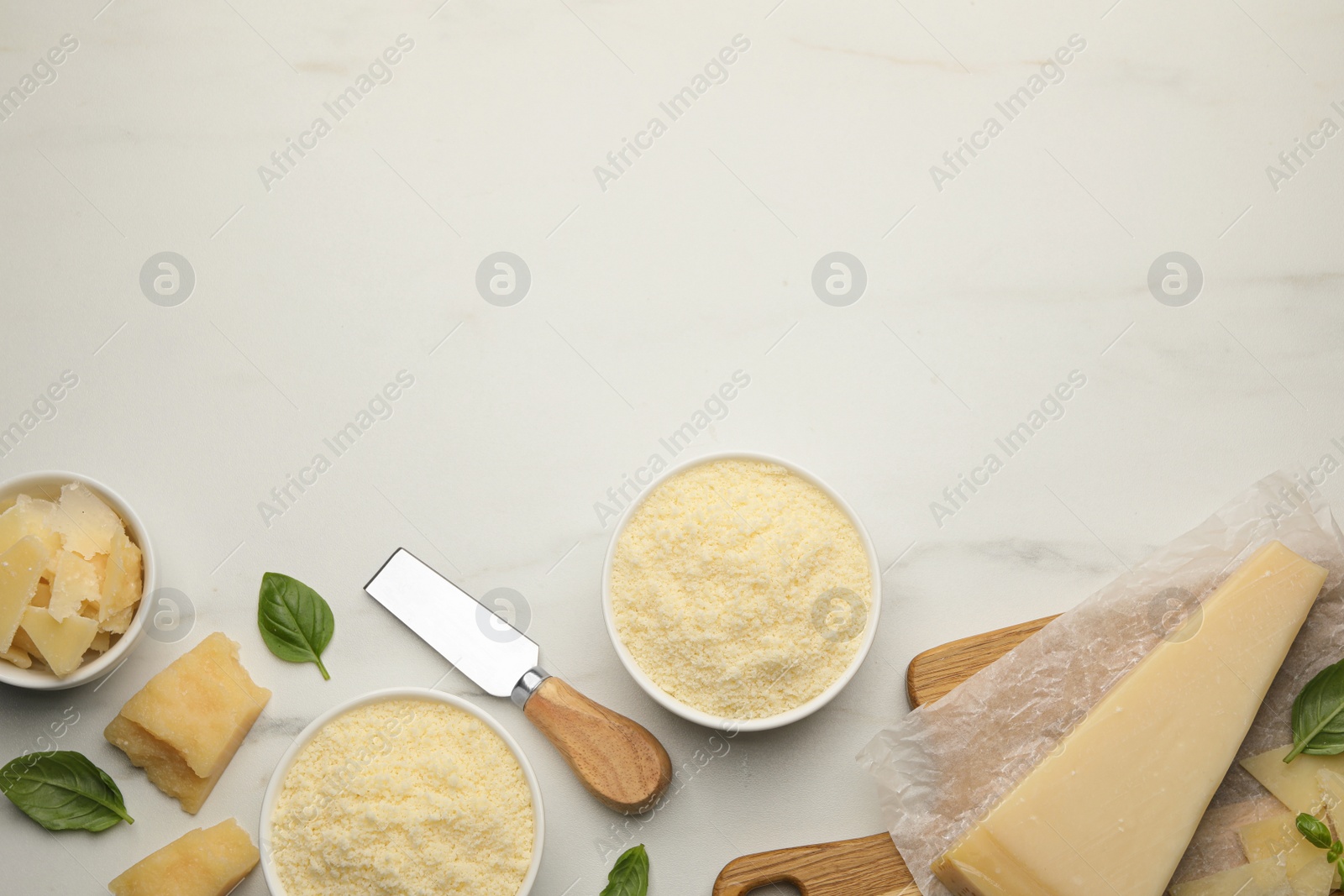 Photo of Flat lay composition with whole and grated parmesan cheese on white marble table. Space for text