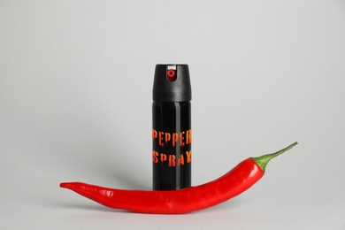 Image of Bottle of gas spray and fresh chili pepper on grey background