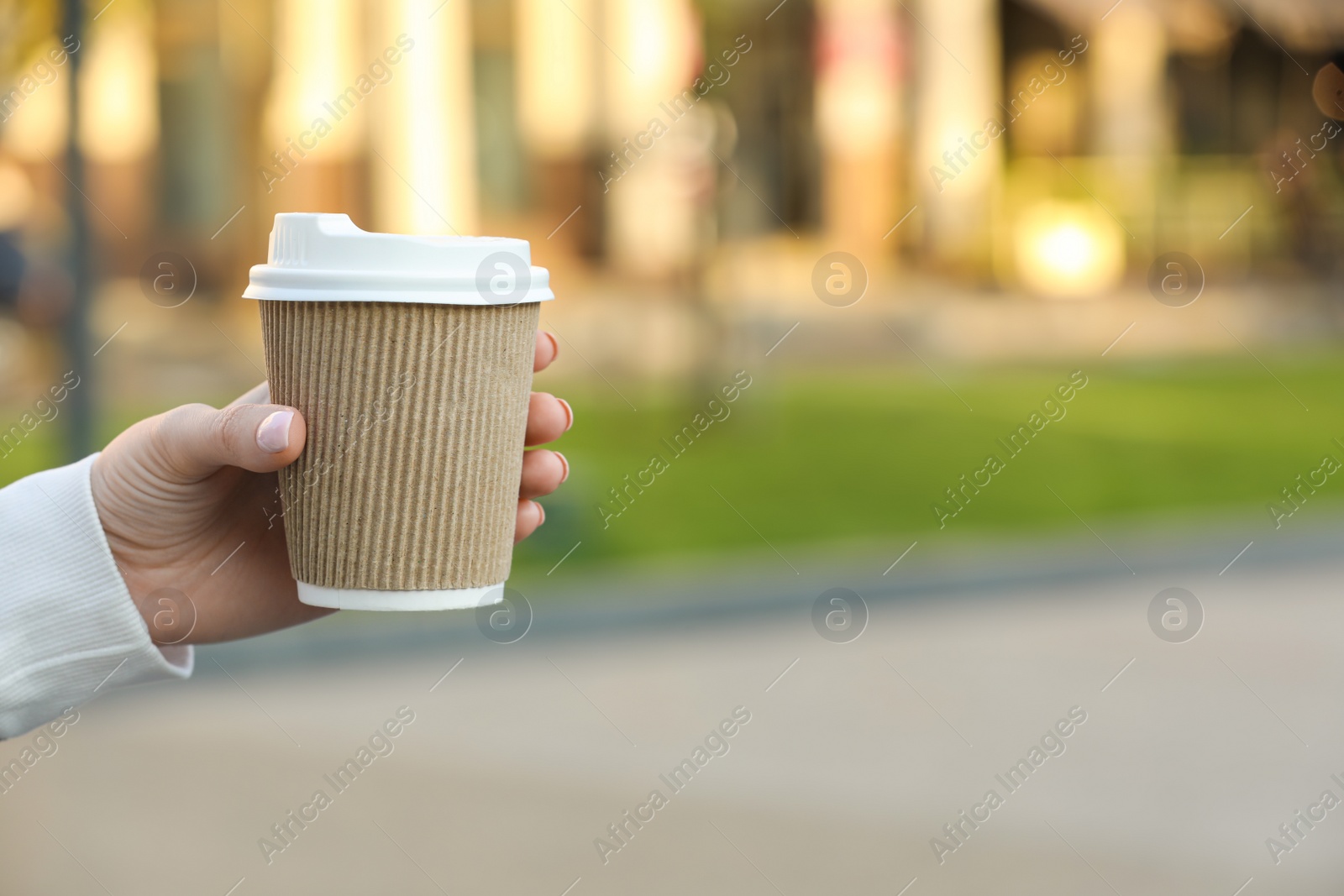 Photo of Woman holding paper takeaway cup outdoors, closeup with space for text. Coffee to go