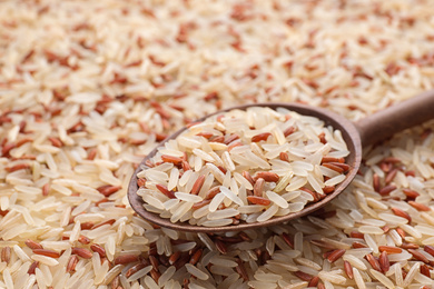 Photo of Mix of brown and polished rice with wooden spoon, closeup