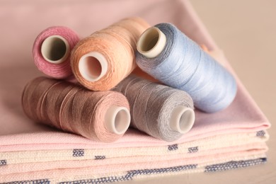 Photo of Set of color sewing threads on light grey table, closeup