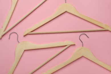 Photo of Empty wooden hangers on pink background, flat lay