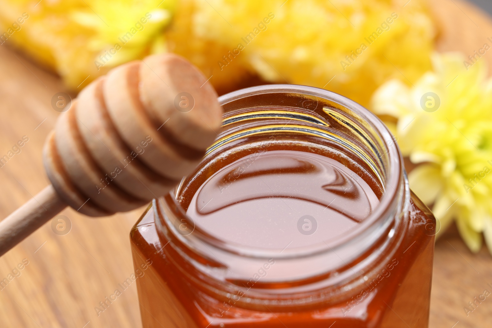 Photo of Sweet honey in jar and dipper on table, closeup