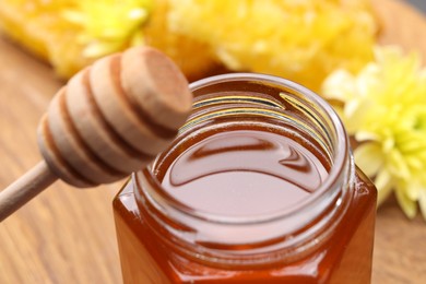 Photo of Sweet honey in jar and dipper on table, closeup
