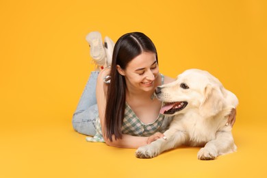 Photo of Happy woman with cute Labrador Retriever dog on orange background. Adorable pet