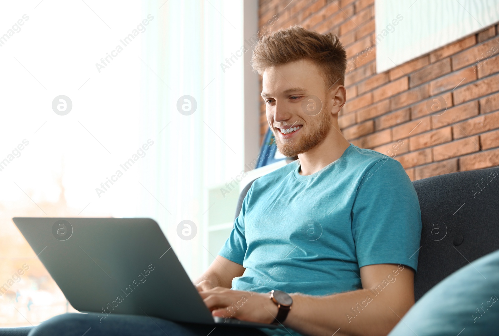 Photo of Young man using laptop in living room