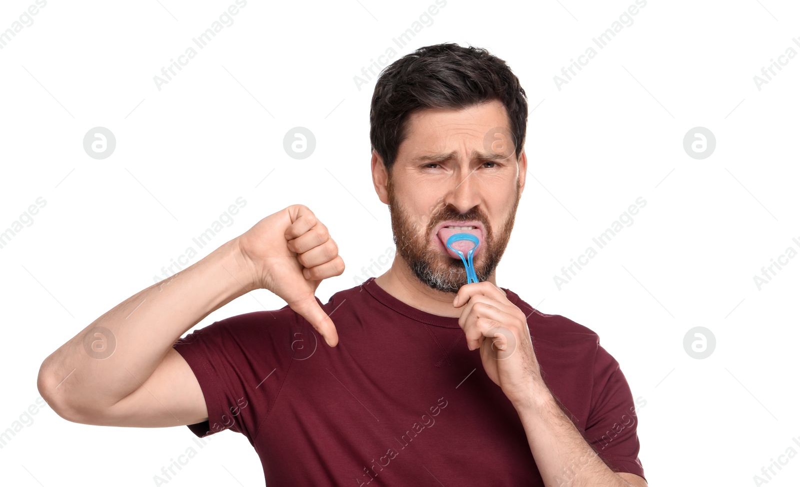 Photo of Handsome man brushing his tongue with cleaner and showing thumb down on white background