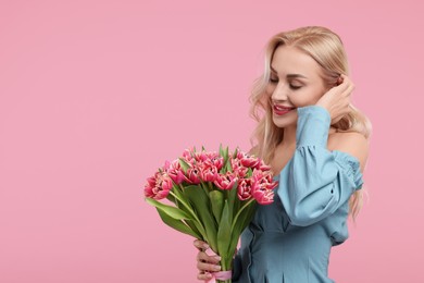 Happy young woman with beautiful bouquet on dusty pink background. Space for text