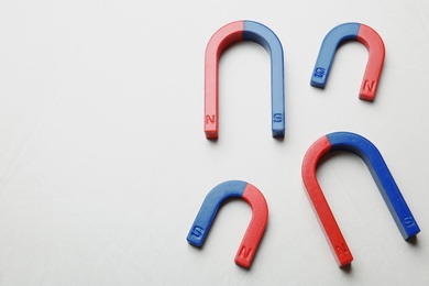 Photo of Red and blue horseshoe magnets on white background, top view with space for text