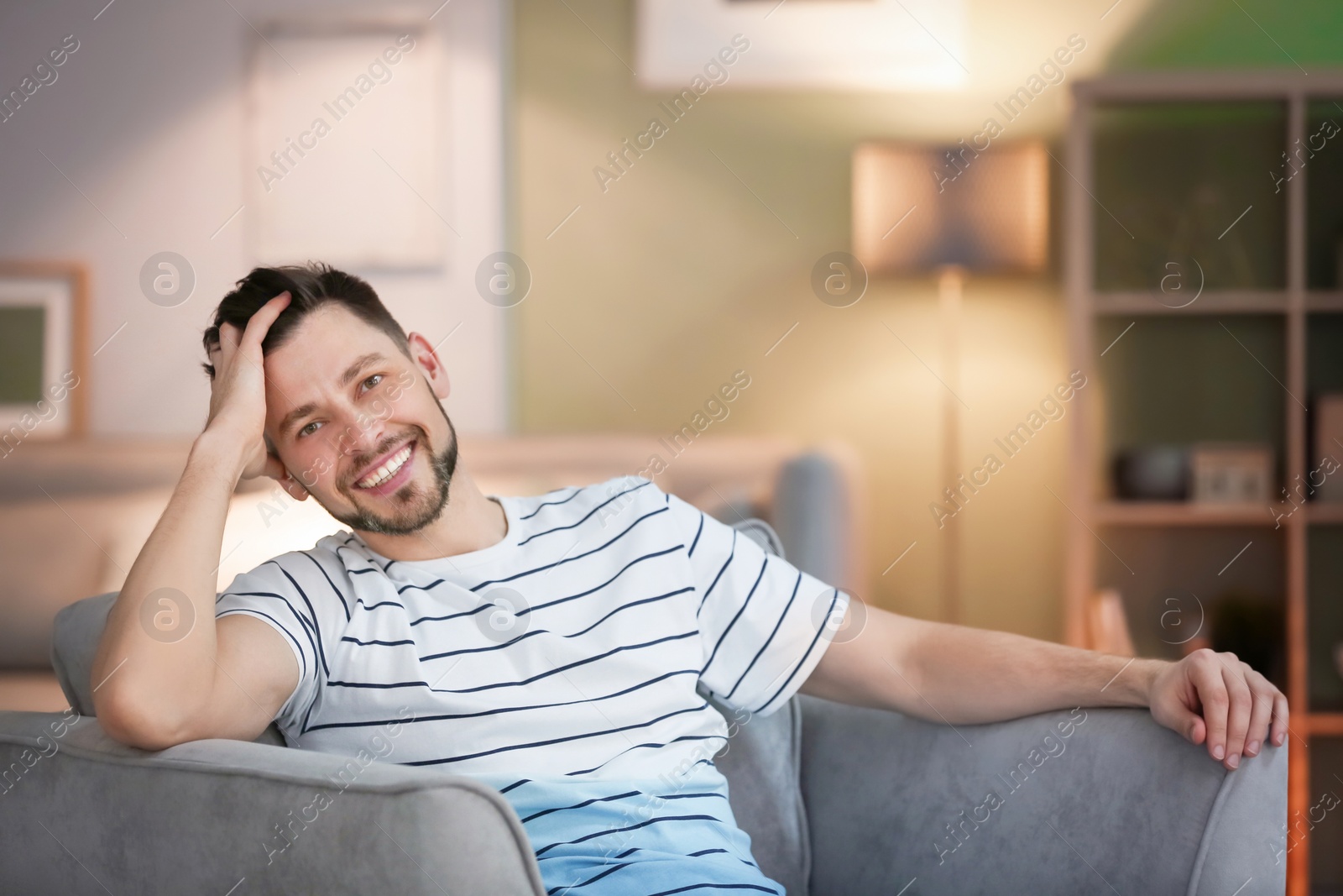 Photo of Young man sitting in armchair at home