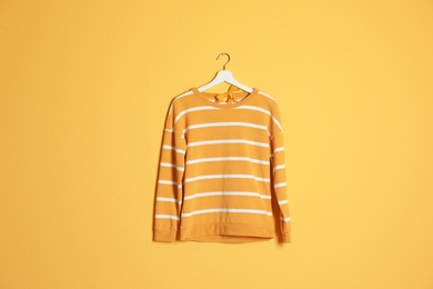 Hanger with stylish sweater on color background