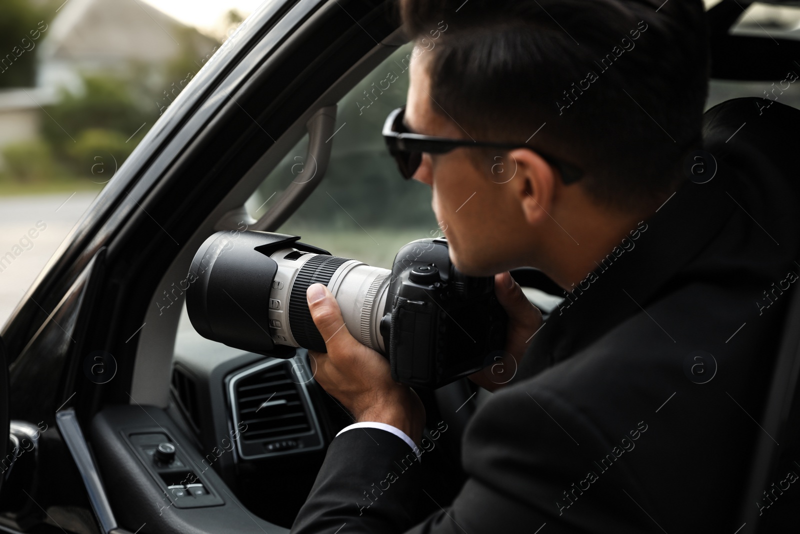 Photo of Private detective with camera spying from car