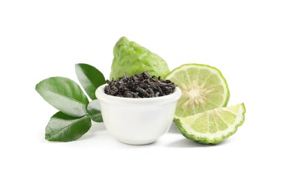 Photo of Dry bergamot tea leaves in bowl and fresh fruits on white background
