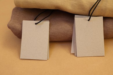 Photo of Garment with cardboard tags on kraft paper sheet, closeup. Space for text