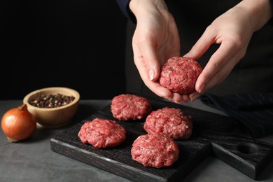 Photo of Woman making meatball from ground meat at grey table, closeup