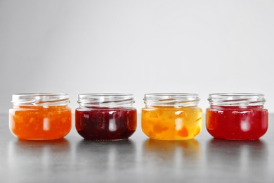 Photo of Jars with different sweet jam on grey background